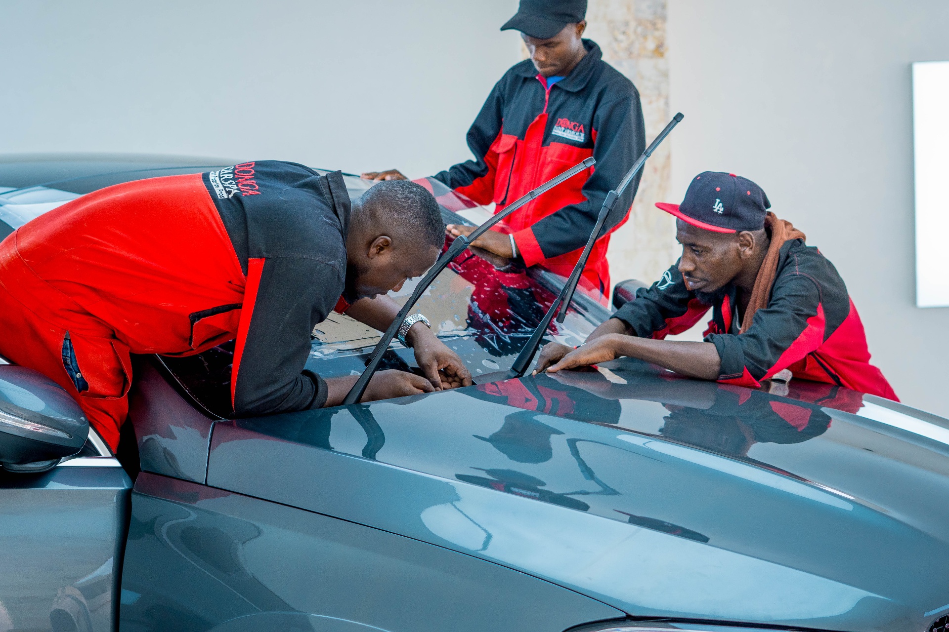 Three Donga technicians fitting windscreen protection on a Mercedes GLE